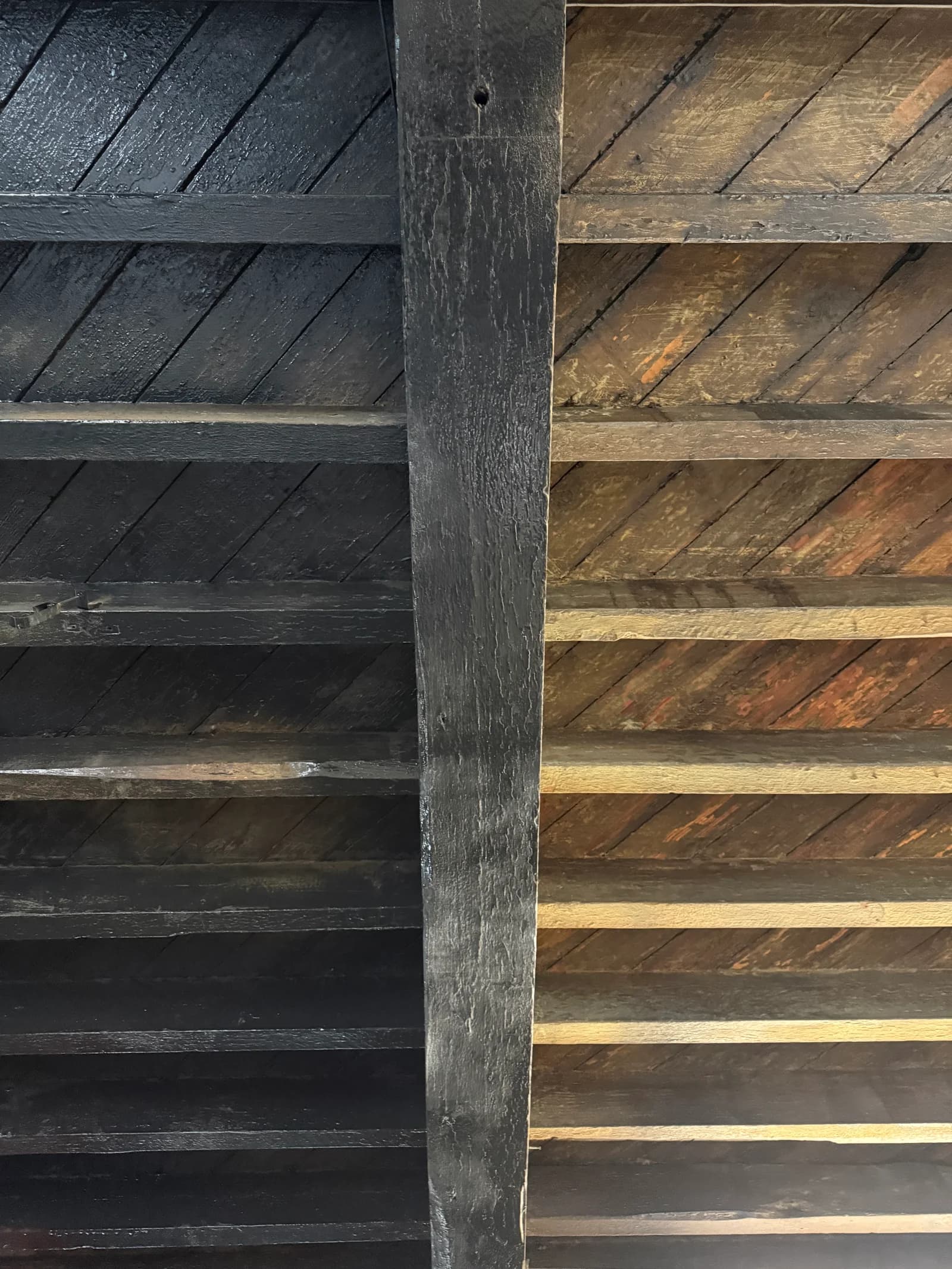 Exposed ceiling beams with black finish beside unfinished timber