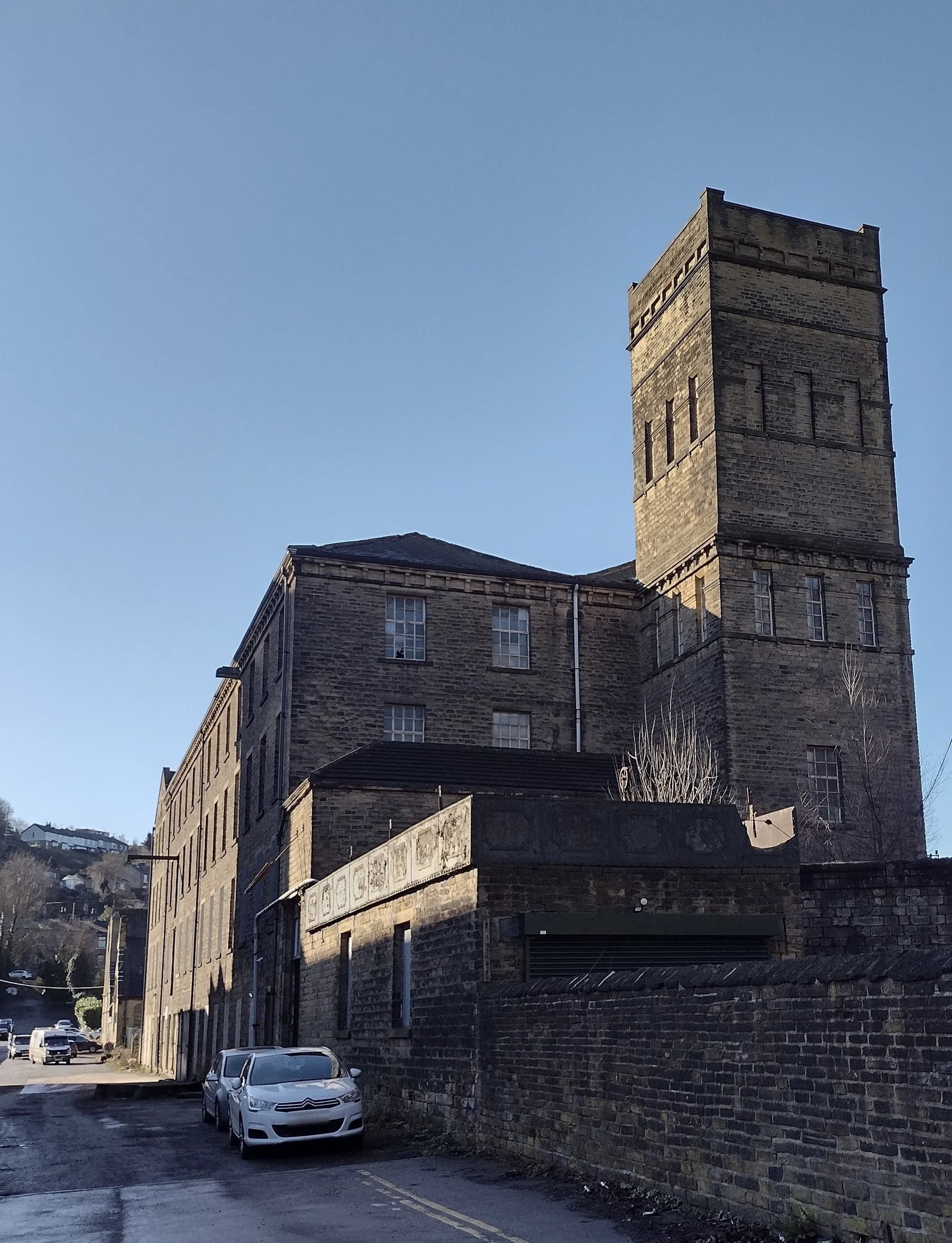 Photograph looking along the side of North Dean Mill towards its stone tower